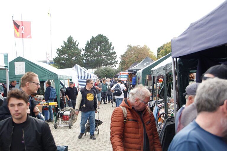Blick auf einen belebten Freiluftmarkt: Menschen gehen zwischen Marktständen und Zelten spazieren.